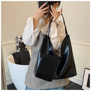 Detail view of a black glossy hobo bag set with twin shoulder straps and a mini pouch