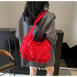 Detail view of bright red pleated cloud bag with scrunchie strap on model shoulder