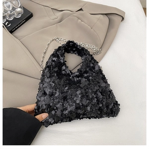 Detailed view of shimmering black sequins and metallic chain on a small designer handbag