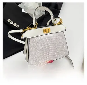 Close-up of white crocodile pattern handbag featuring a metal turn-lock and handle