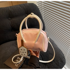 Detailed view of pink and white bowling handbag with round handles and detachable strap