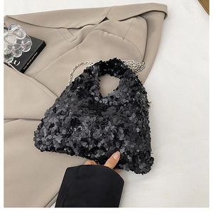 Close-up of black sequined crossbody bag with silver chain on beige blazer background