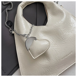 Detail of off-white wrinkled leather handbag with heart pendant and silver chain