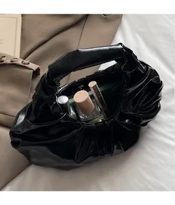 Detailed interior of a glossy black pleated dumpling bag showing spacious storage capacity