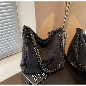 Detailed shot of dark gray denim tote with metal studs and woven chain strap details