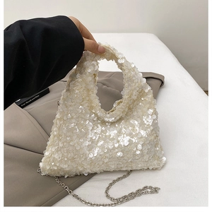 Close-up of white sequin handbag with metallic chain strap and textured shimmer detail