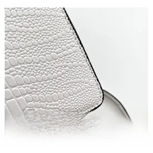 Detailed macro view of white crocodile pattern texture and black stitched edges on handbag
