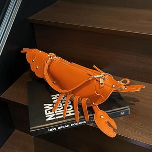 Detailed close-up of a creative orange lobster-shaped crossbody bag on a wooden surface