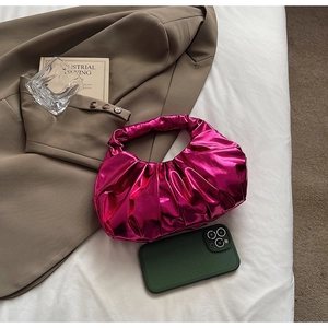 Metallic pink pleated wrist bag shown next to an iPhone to demonstrate compact size