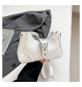 Nahaufnahme der weißen Schultertasche aus Leder mit Nieten und Y2K Schnallendetails