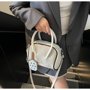 Detalle de bolso Boston blanco con borde negro y colgante de raqueta llevado por modelo