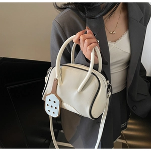 Detail of white contrast bowling bag with black piping and racket-shaped charm detail
