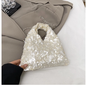Detailed view of white sequined handbag with triangular shape and silver chain strap