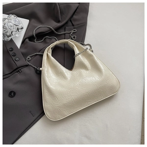 Detail of cream pleated faux leather bag with delicate silver chain on a gray blazer