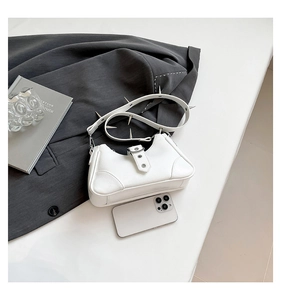 Detail der weißen Handtasche mit Litschi-Muster und silbernen Punk-Nieten am Schultergurt