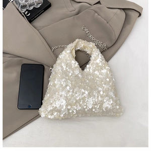 Detailed macro view of white round sequins on a stylish triangle-shaped handbag with chain