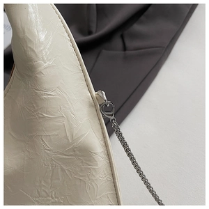 Detailed close-up of cream white pleated leather texture and silver chain strap