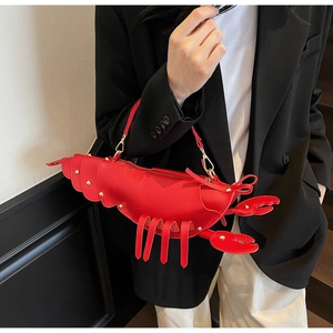 Detail of red lobster-shaped handbag with golden rivets and shiny leather texture
