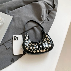 Minimalist black crescent moon bag with silver rivets on a grey textured background
