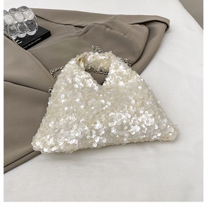 Detail of white sequin handbag with silver chain strap on a grey blazer suit