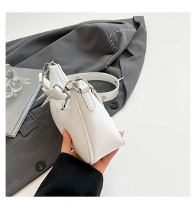 Detail der weißen Handtasche aus Leder mit silbernen Punk-Nieten und Metall-Hardware