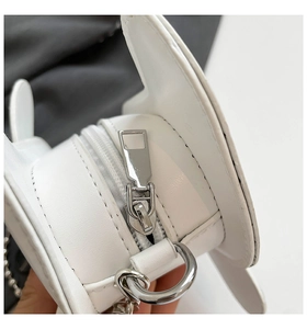 Close-up of white wing-shaped mini bag showing lychee grain texture and metal zipper