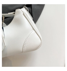 Detailaufnahme der weißen Kunstledertasche mit Narbenstruktur und silbernen Nieten