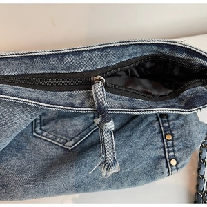Λεπτομέρεια macro από πλυμένη μπλε τσάντα denim με φερμουάρ και προσεγμένες ραφές