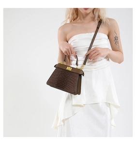 Detailed view of brown crocodile texture handbag with gold twist lock and top handle