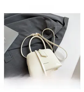 Detailed view of white patent leather handbag with adjustable strap and metal studs