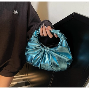Detail view of the metallic blue pleated handbag with a unique knotted handle design