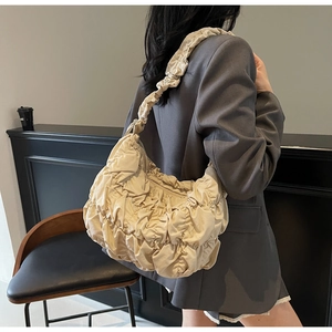 Detailed view of beige pleated cloud bag showing soft texture and wide shoulder strap