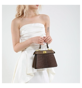 Close-up of brown crocodile pattern leather handbag with gold twist lock hardware
