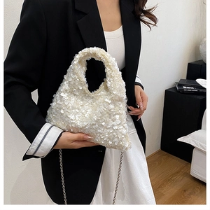 Detail of white sequin dumpling bag with metallic chain strap and textured finish