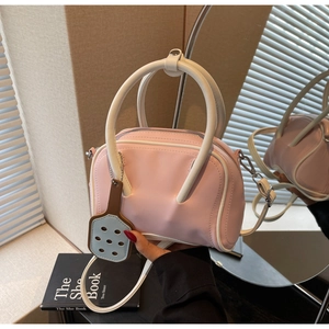 Detail of macaron pink Boston bag featuring contrasting white handles and shoulder strap