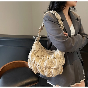 Detail of beige pleated puff tote bag with cloud texture on a shoulder strap