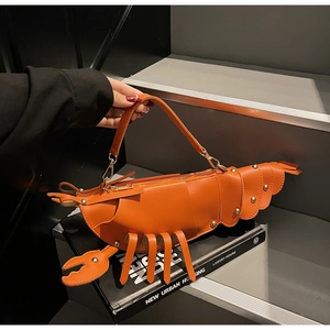 Detail of creative orange lobster-shaped bag with glossy leather and gold rivet accents