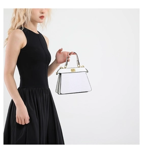 Detail of white crocodile pattern handbag with gold twist lock and accordion sides
