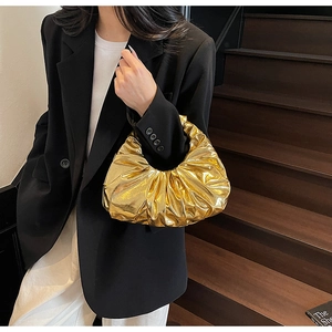 Golden pleated wrist bag with metallic finish shown styled with a black blazer
