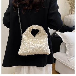 Close-up of white sequin texture and metallic chain strap on a designer handbag