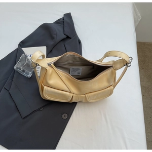 Close-up of cream yellow shoulder bag featuring front bow-knot pockets and zip closure