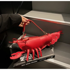 Close-up of a creative lobster-shaped red handbag with gold rivets and zipper detail