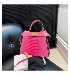 Detailed macro view of pink crocodile embossed leather and golden metal turn-lock on the bag