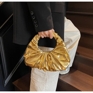 Detail of a metallic gold pleated crescent moon bag with a modern wrinkled texture finish