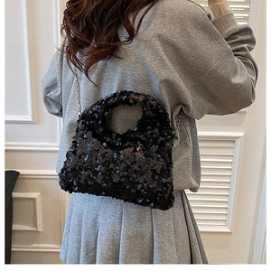 Detail of a chic black sequined crossbody bag with silver chain strap worn by a model