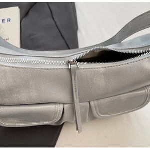 Macro detail of silver hobo bag featuring twin flap pockets and premium metal zipper