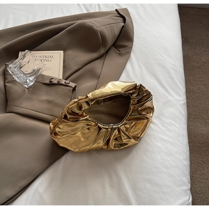 Close-up of gold metallic cloud pouch with natural pleats and magnetic closure