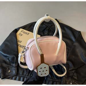 Pink Boston handbag with white contrast trim and a unique colander charm on a leather jacket