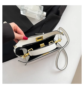 Macro shot of white leather handbag interior showing black compartments and gold hardware