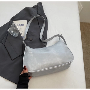 Detail of silver metallic hobo bag with adjustable strap on minimalist background